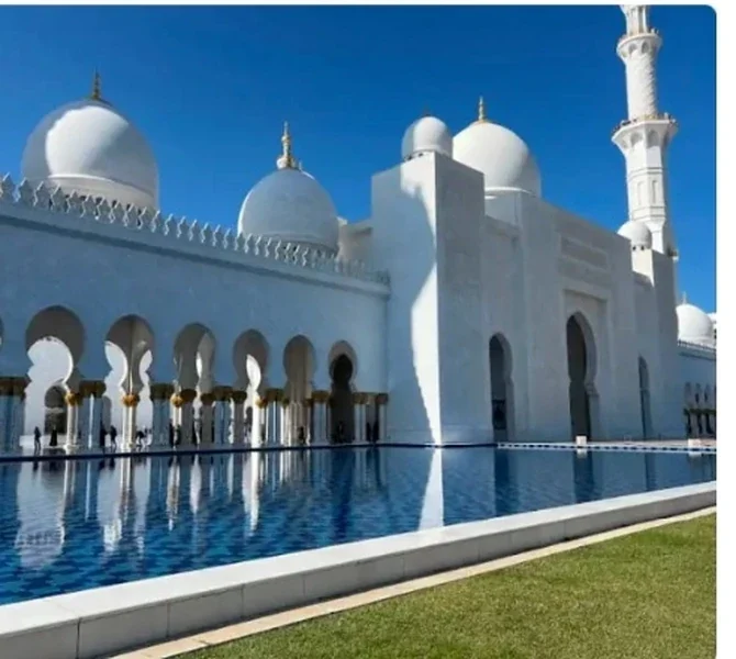White domes of the grand mosque reflected in water