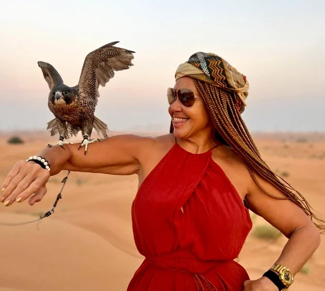 A falcon landing on Lisa's arm in the desert