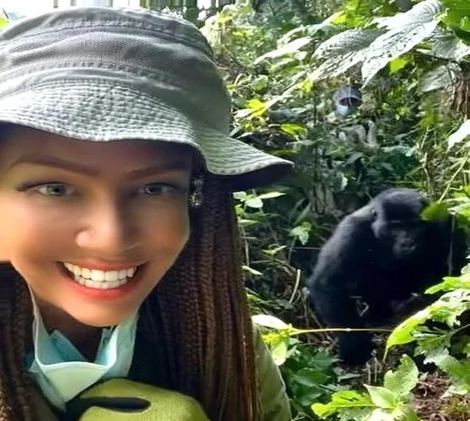 Lisa smiling with a gorilla behind her in the forest