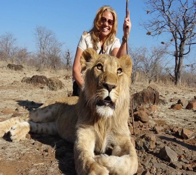 Lisa standing behind a resting lion