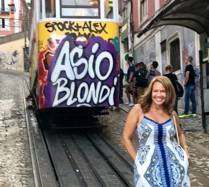 Lisa beside a graffiti-covered tram in Lisbon