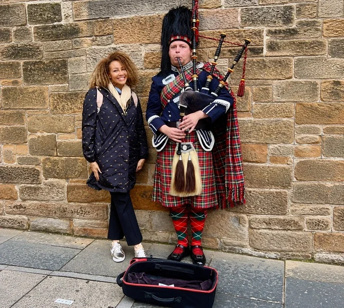 Lisa beside a bagpiper in full Highland dress